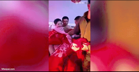 新郎被扒得只剩一条内裤,一群宾客围在床边扒闹洞房,新娘和新郎坐在床