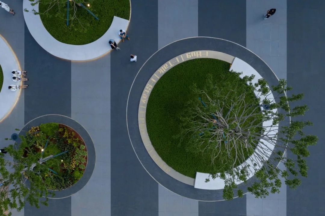 人们三三两两围坐谈天△开放的城市界面△直线与圆形的穿插交融场地